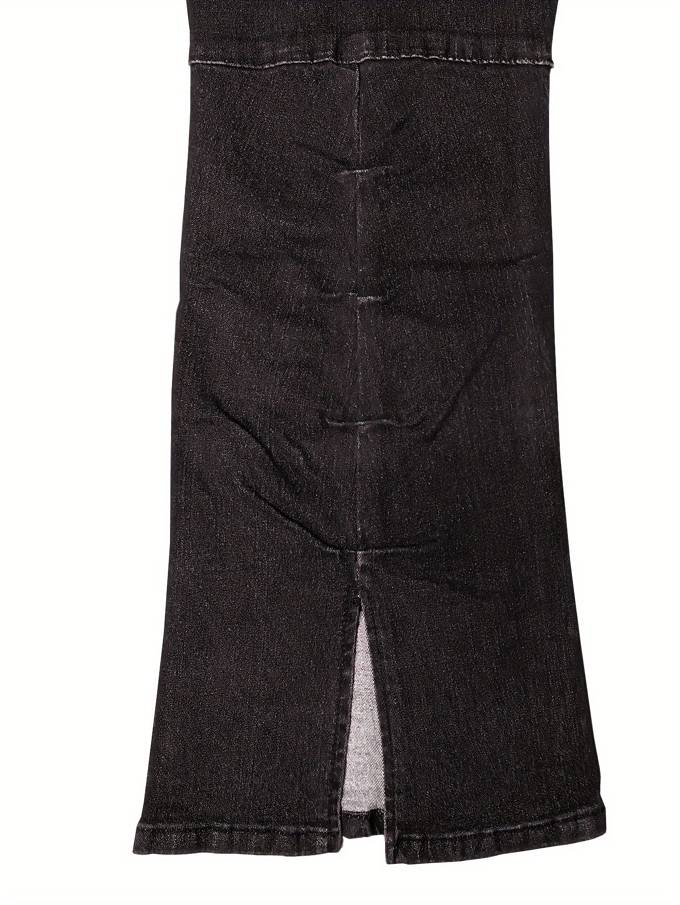 Close-up of black high-waisted plus size bell bottom jeans with a split hem detail, showcasing the stretch denim fabric.