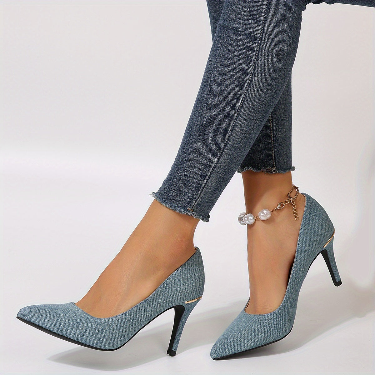 Woman wearing stylish blue high heels with denim jeans and a pearl ankle bracelet.