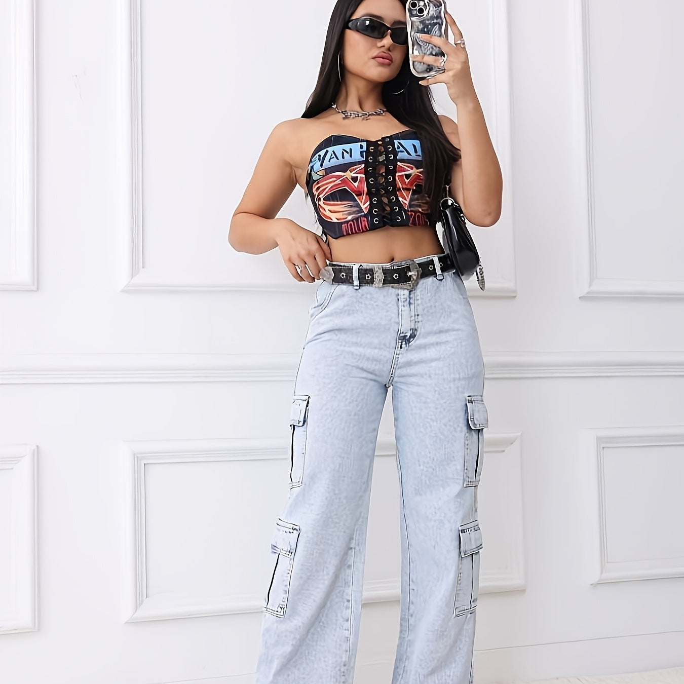 Woman in a stylish cropped top and retro blue cargo jeans, showcasing a casual and trendy outfit against a white background.