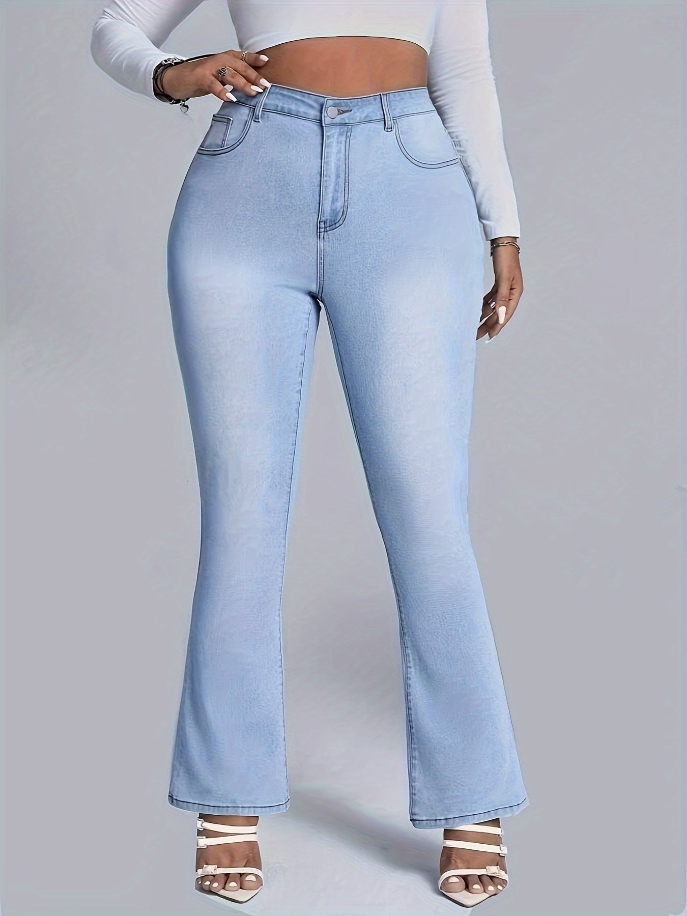 Chic plus size women's embroidered butterfly flare jeans in stretch denim, light wash, styled with white top and heels