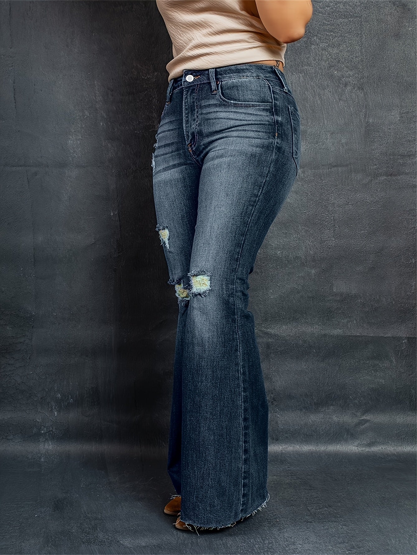 Stylish plus size high-rise flared leg jeans with ripped details on a curvy woman, showcasing comfortable and casual wear.