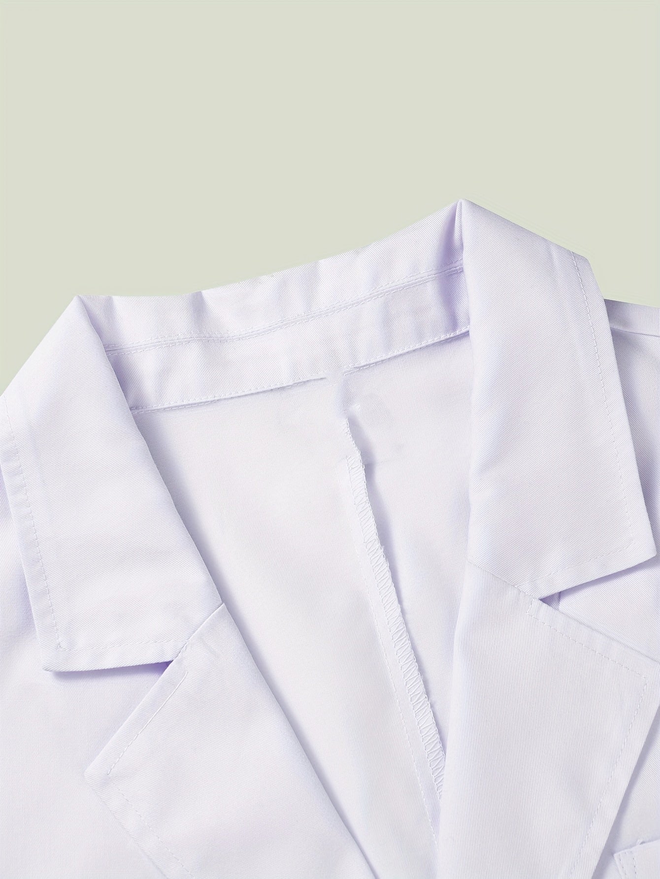 Close-up of white Middle Eastern style lab coat with lapel collar, polyester-cotton blend fabric, showing detail of open-front design.