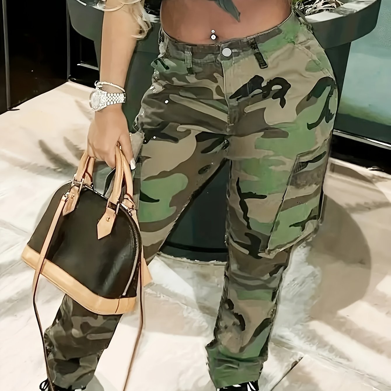 Plus size women's camo print cargo jeans with button fly and multiple pockets, paired with a stylish handbag, perfect for casual wear.