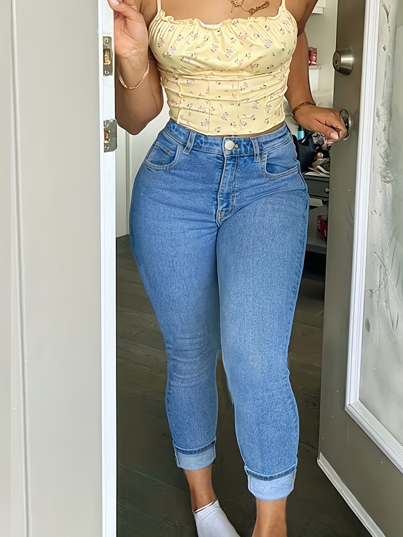 Plus size woman wearing high-waisted, stretchy skinny fit denim pants in washed blue with a zipper button closure, styled casually with a yellow top.