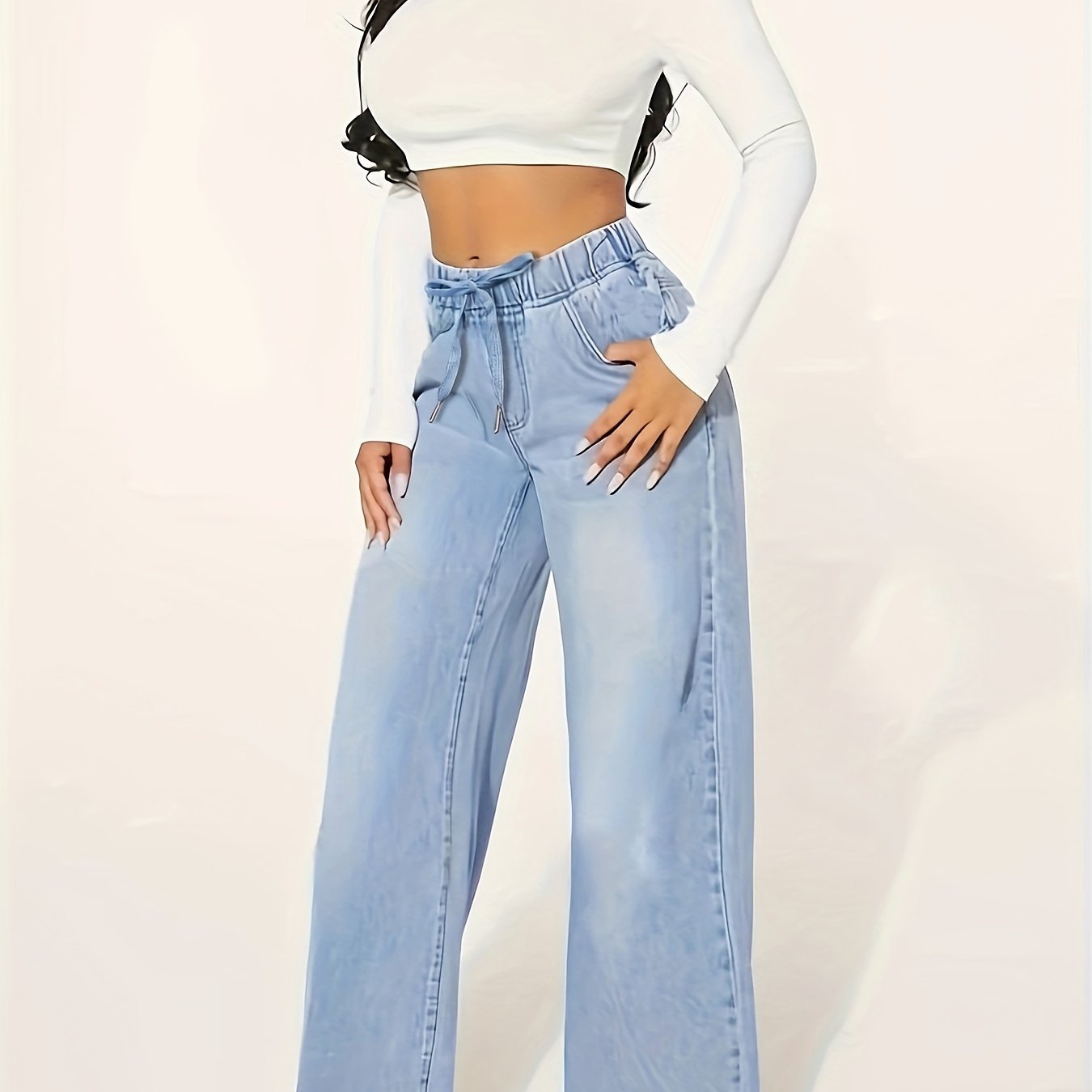 Plus Size Women's loose fit jeans with drawstring elastic waistband in classic washed blue color, styled with a white crop top.