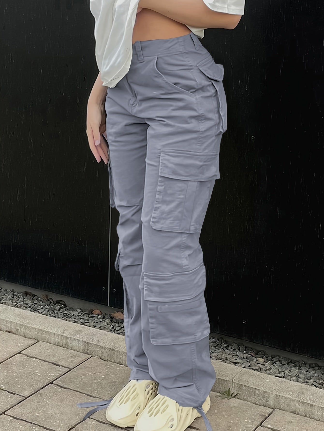 Woman wearing plus size Y2K inspired streetwear cargo jeans with side flap pockets, distressed denim, and high-waisted fit.