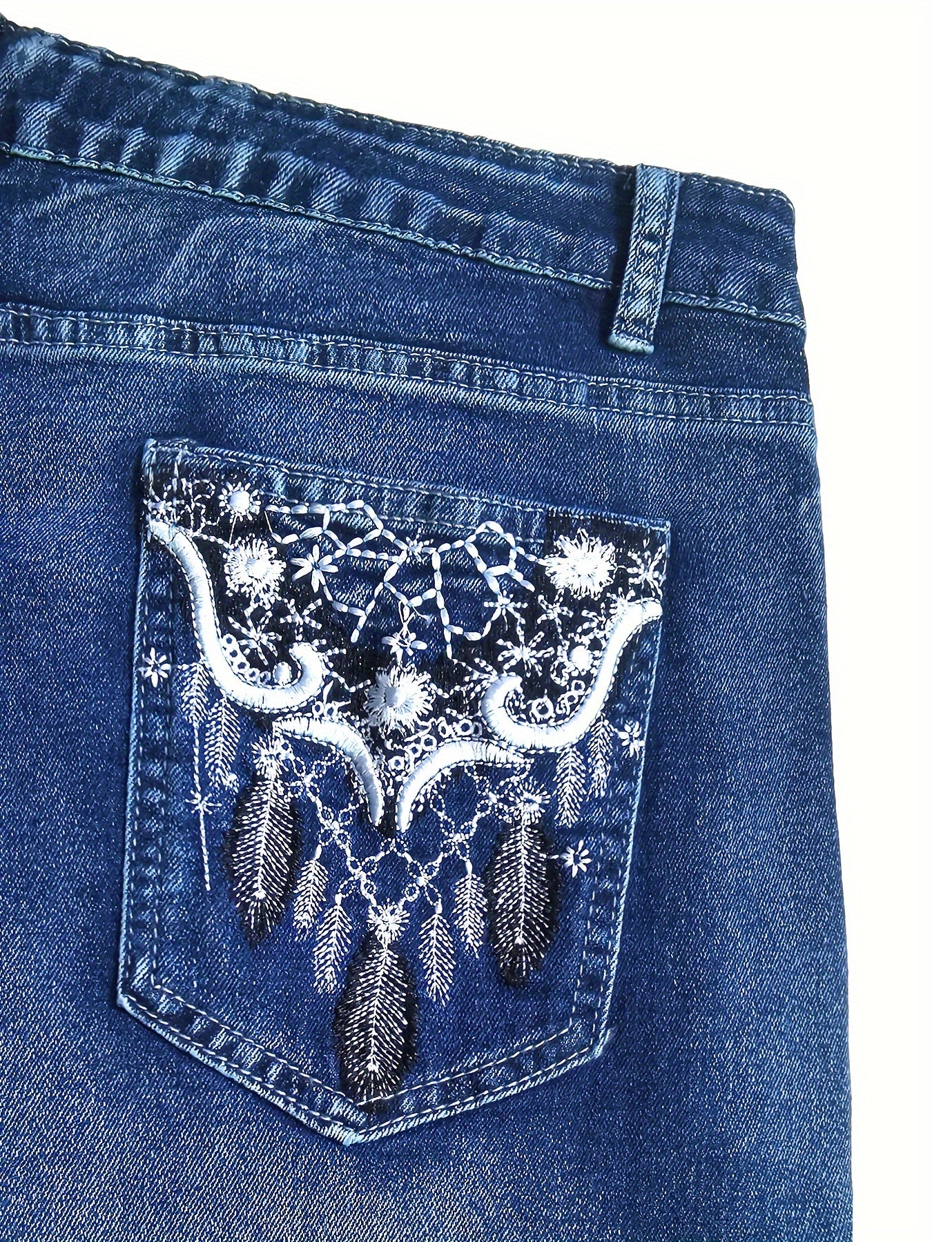 Close-up of back pocket embroidery on plus size washed blue vintage style bootcut denim pants with geometric pattern.