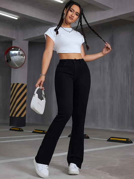 Woman wearing Stretchy High-Rise Bootcut Jeans in black, paired with a white crop top and white sneakers, holding a small white handbag.